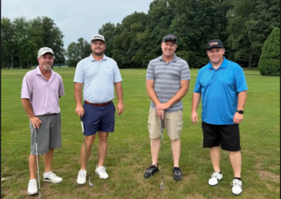 Group of 4 men in golf clothing in front of trees