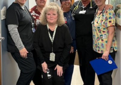 Women in scrubs of various colors and patterns stand posed together.