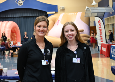 Two blonde women in black quarter zips stand posed together