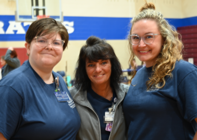 Three women stand posed smiling.