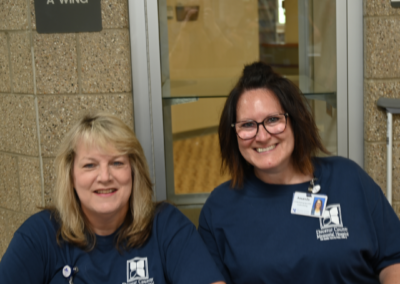 Two women in navy t-shirts siting behind a table