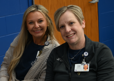 Two women with blond hair sitting next to each other posed together.