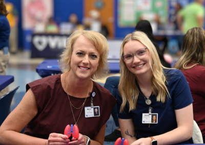 Two women with blond hair sit at a table holding a toy.