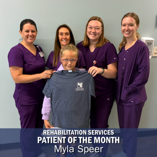 4 Women in purple scrubs stand behind a young girl in a navy tshirt